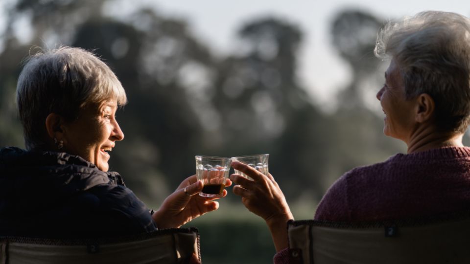 Dos mujeres sonriendo mientras beben café disfrutando de su longevidad
