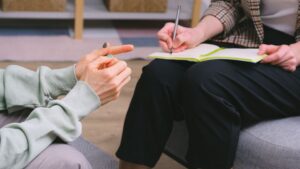 Mujer explicando su situación a una psicóloga que toma notas durante una sesión de terapia