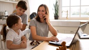 Madre trabajando desde casa mientras cuida a sus dos hijos, excedencia por cuidado de hijos